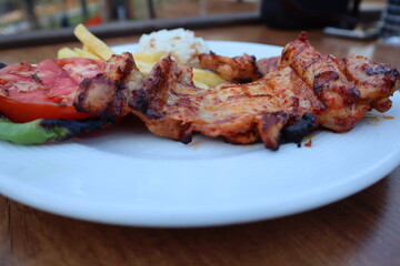 Grilled chicken with rice, french fries, roasted tomatoes and peppers