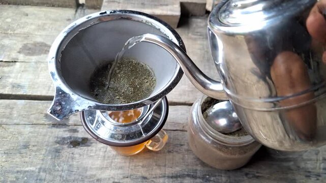 Green kratom leaf powder (Mitragyna speciosa) being brewed using a stainless steel strainer. The herbal drink is known for its traditional use in some cultures