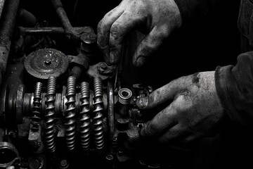 A skilled mechanic inspects the electrical nozzle injector of a bulldozer track-type tractor in a workshop, performing repair and maintenance on heavy machinery.