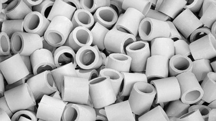 A pile of white cylinders with a white background. The cylinders are of different sizes and are piled on top of each other