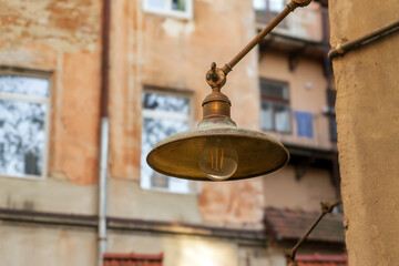 Fototapeta premium Vintage brass lamp on historic building wall. Old-Fashioned lantern on urban building.Retro exterior lighting