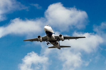 The plane flies through a clear blue sky, surrounded by fluffy white clouds. Travel and adventure...