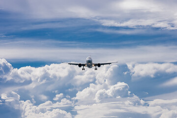 The plane flies through a clear blue sky, surrounded by fluffy white clouds. Travel and adventure concept.
