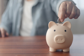 Man putting coins in piggy bank and taking notes in notebook money saving concept business