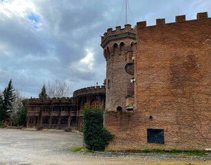 Brick fortress tower Cylindrical brick tower with battlements forming part of a fortress wall beneath a partly cloudy sky. © Victoria