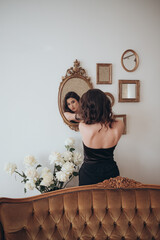 woman in black dress checking her reflection in a vintage mirror