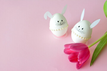 handmade Easter bunny eggs with tulip on a pink background