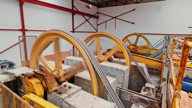 Industrial stone-cutting machines with a moving gear system. Large pulley systems driven by powerful motors play a crucial role in marble production.