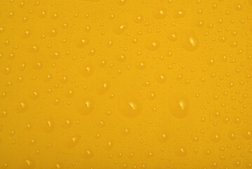 Yellow plastic with water drops. Abstract mustard color background.