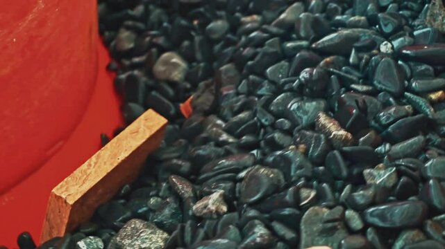 Industrial stone polishing operation. Marble chips are polished inside a tumbler with abrasive pebbles.