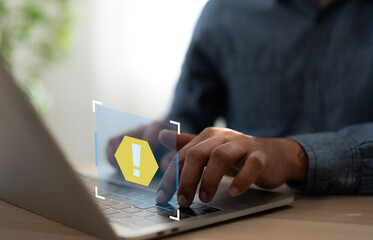 A Businessman working on a laptop open email with triangle caution warning sign for notification...