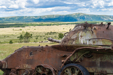 Old destroyed Russian tank on a grassy field
