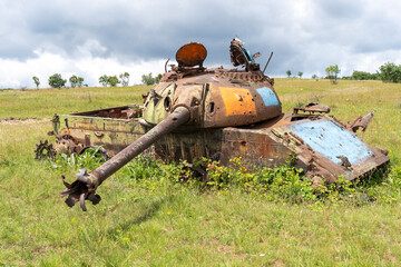Old destroyed Russian tank on a grassy field