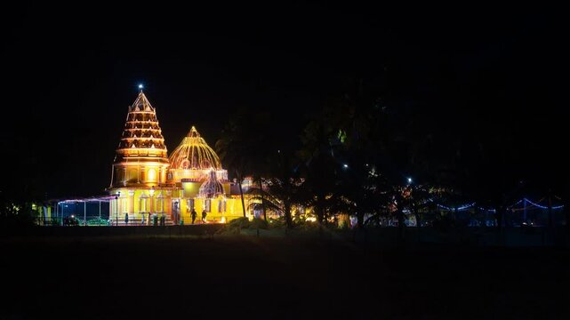 4k Hyper Lapse Timelapse of decorated and lit up Sri Siddhapurush Narayandev temple at Kankabandh Mapusa with locals and devotees visiting it at night during festival