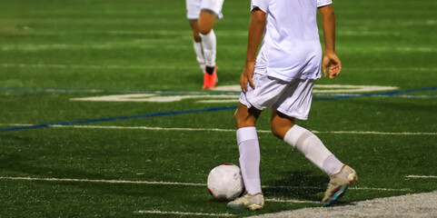 Young Soccer Player Prepares to Kick the Ball During a Night Game on a Well-Lit Field
