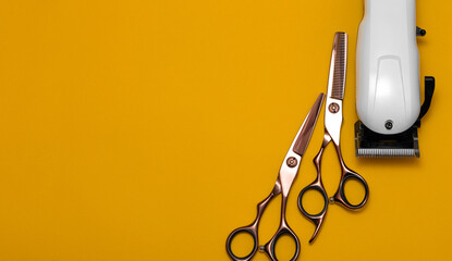Hairdressing and barber tools. Professional scissors and hairdressing clipper. Bright yellow background. The concept of hair care and professional grooming. Copy space for marketing materials, banners