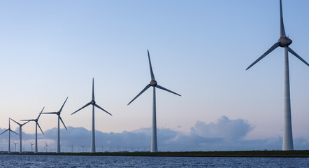 Row of offshore wind turbines against dark sky blue in Netherlands