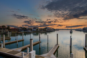 Obraz premium A gorgeous landscape with ocean water, homes and boats on the water, blue sky and clouds, lush green palm trees at sunrise in Clearwater Florida USA