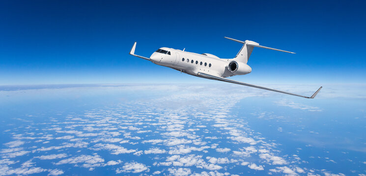 White private jet flying above clouds in blue sky