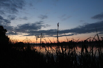 Obraz premium dark silhouettes against the background of a sunset over the river. Evening Landscape