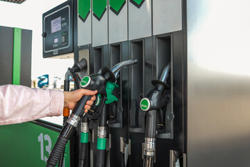 Close-up of a person holding a diesel fuel nozzle at a modern gas station. Fuel dispensers with...