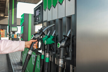 Close-up of a person holding a diesel fuel nozzle at a modern gas station. Fuel dispensers with...