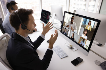 Focused contact center manager man in headset talking to diverse group of colleagues, partners on...