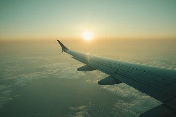Obraz premium Airplane Wing Overlooking Clouds and Sunset During Flight in a Clear Sky