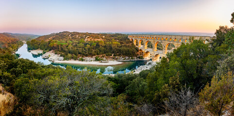 Pont du Gard, ancient Roman aqueduct bridge, elevated panoramic view, river bend and arches, early morning golden light, Gorges du Gardon, natural landscape, UNESCO Biosphere Reserve, Provence, France