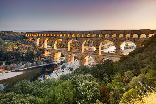 Pont du Gard, ancient Roman aqueduct bridge, elevated view, river bend and complete arches, early morning golden light, Gorges du Gardon, natural landscape, UNESCO Biosphere Reserve, Provence, France