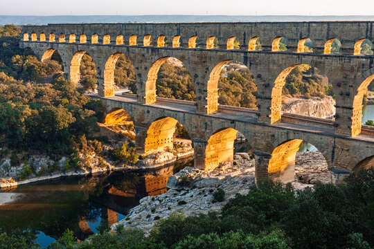 Pont du Gard, ancient Roman aqueduct bridge, elevated view, river bend and complete arches, early morning golden light, Gorges du Gardon, natural landscape, UNESCO Biosphere Reserve, Provence, France