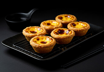 Delicious Pastel de Nata Custard Tarts in a Dark Moody Setting. Traditional Portuguese dessert with a crispy crust and creamy filling, styled on a black tray for gourmet appeal , food, menu,