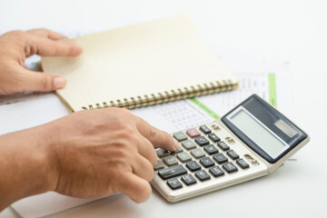 Hand pressing buttons on calculator while preparing financial reports in an office setting