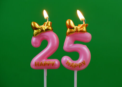 Burning pink birthday candles with golden bow and word happy on green background, number 25.