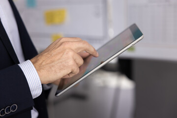 Tablet computer in hands of businessman close up. Unrecognizable business professional man typing on digital pad screen, using Internet technology for job communication. Cropped shot