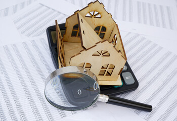 Destroyed house on calculator under magnifying glass on financial data concept. Repair house price.