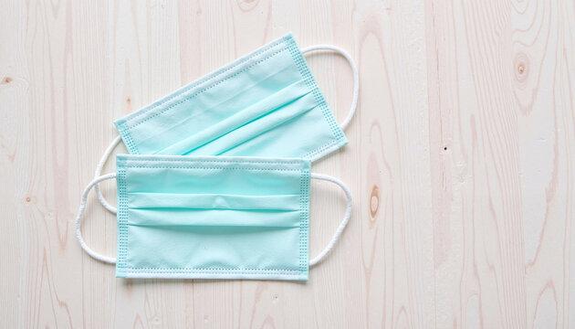Pastel-colored allergy masks lying on light wooden surface, health awareness - Powered by Adobe