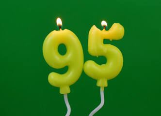 Air balloon shaped birthday candles burning on green background. Number 95.