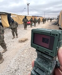 Soldiers in camouflage uniforms standing near a temporary structure outside