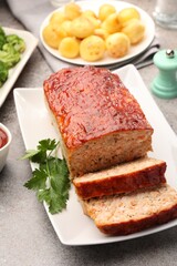 Delicious baked turkey meatloaf with vegetables served on grey table, closeup