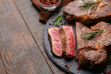 Pieces of delicious beef meat and spices on wooden table, closeup. Space for text