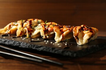 Tasty fried gyoza (dumplings) and chopsticks on wooden table, closeup