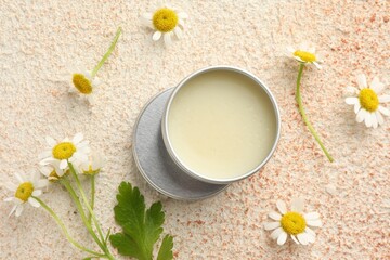Moisturizing lip balm and beautiful flowers on color textured table, flat lay