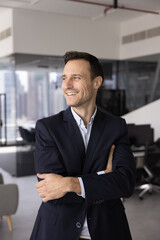 Fototapeta premium Cheerful confident Latin company executive man keeping arms folded at chest in confidence gesture, looking away, smiling, laughing, thinking on job success, successful work project. Vertical shot