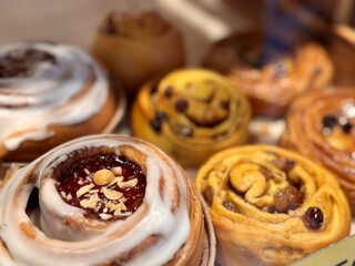 A Delicious and Tempting Assortment of Freshly Baked Sweet Rolls and Scrumptious Pastries. Enchanting display of freshly baked, golden sweet rolls with a variety of delightful fillings and toppings