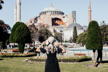Young woman in hat enjoying the view of Hagia Sophia mosque, Istanbul, Turkey