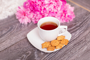 Sweet morning breakfast - cup of tea, cookies and bouquet of peonies flowers
