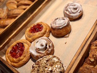 Indulge in the Delicious Bakery Pastries Now Beautifully Arranged on Display for All. In a charming bakery, discover a delightful assortment of freshly baked pastries like cinnamon rolls and Danishes