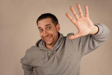 A man raises his open palm in a friendly greeting or farewell. His warm expression enhances the welcoming gesture. The scene conveys positivity and approachability.