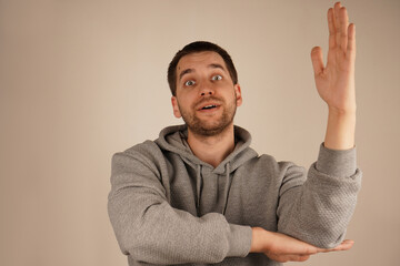 A man holds one elbow with his hand and lifts the other arm, creating a pose of someone an answer. His open gesture and steady posture show interest. The moment exudes energy and positivity.